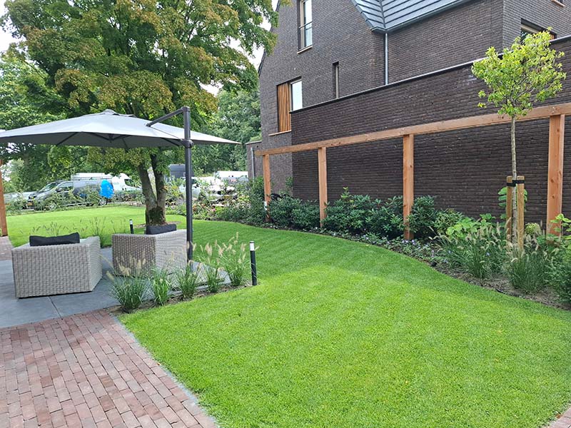 nieuwbouwtuin-coudewater-bersselaargroen Natuurlijke tuin bij een nieuwbouwwoning in Rosmalen met een bestaande volwassen boom, bloeiende vaste planten en een ruim groen gazon.
